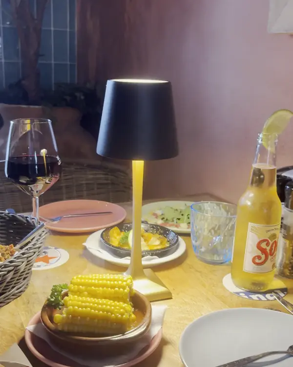 Gedekte tafel bij La Cubanita met maïskolf, wijn en tafellamp