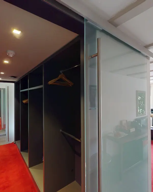 Inloopkast met glazen schuifdeur in de Luxe Kamer met Bad