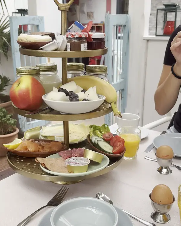 Etagère met ontbijt: fruit, broodjes, kaas en eitjes