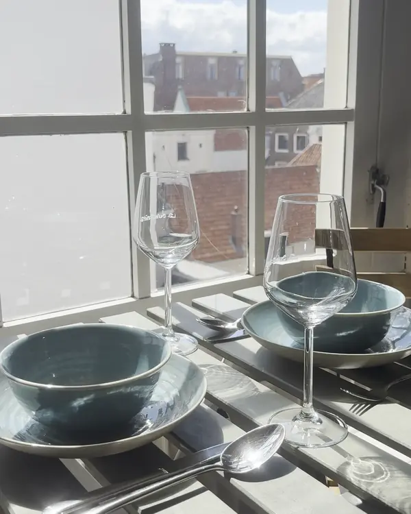 Gedekte ontbijttafel bij het raam met uitzicht over de daken van Zwolle